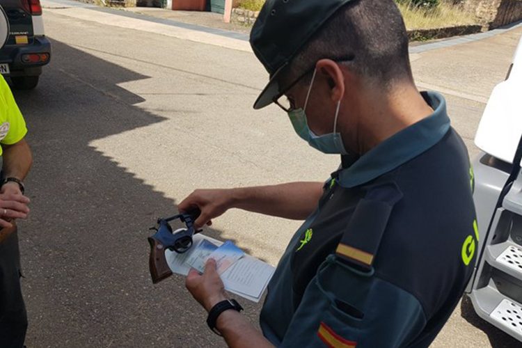 Un guardia civil inspecciona el arma de un vigilante de seguridad.