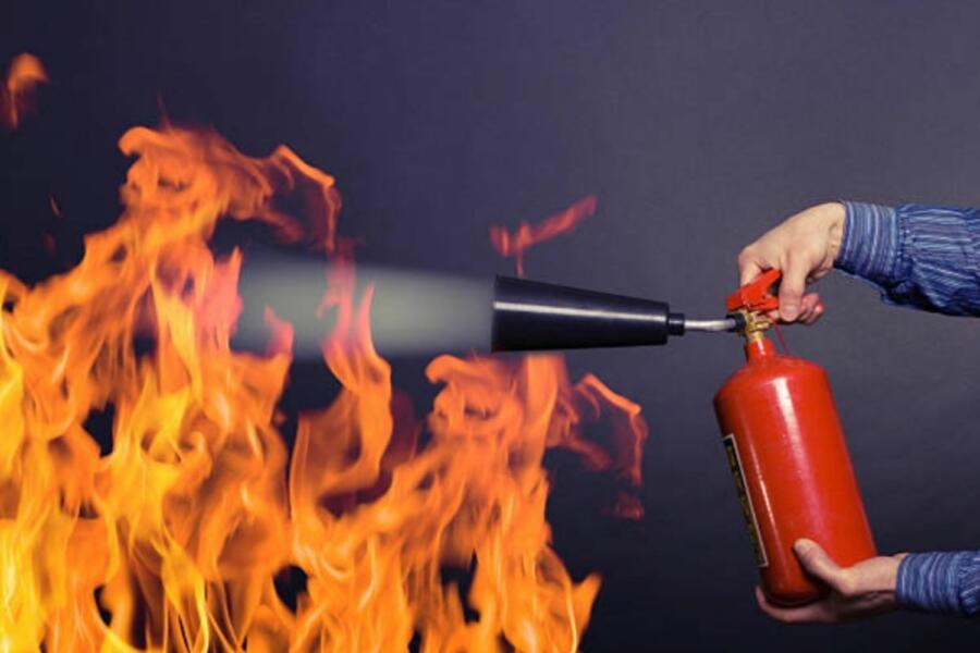 Una persona utiliza un extintor rojo para apagar un incendio. Fuente imagen: Unsplash