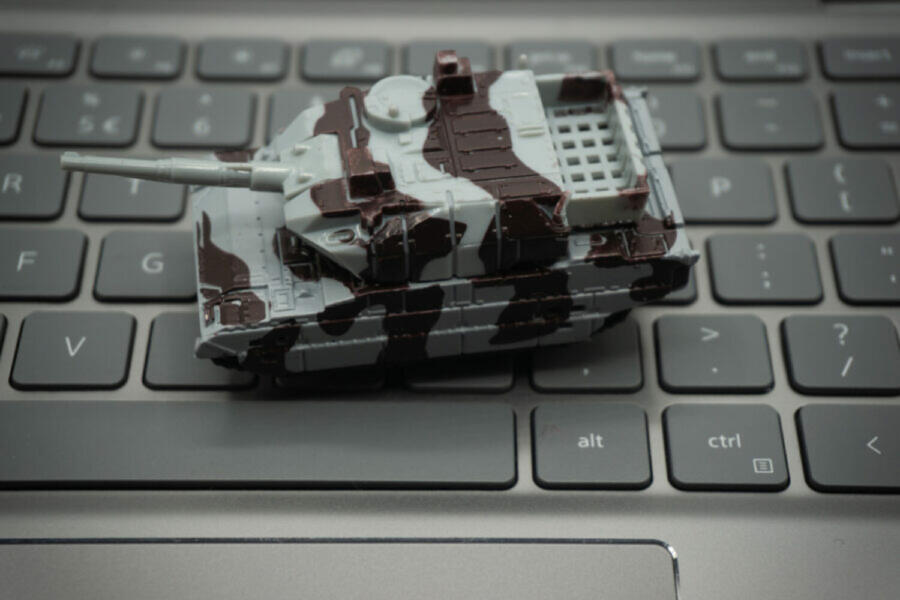 Computer keyboard with tanks on it. An allusion to cyber warfare and the concept of cyber attacks.